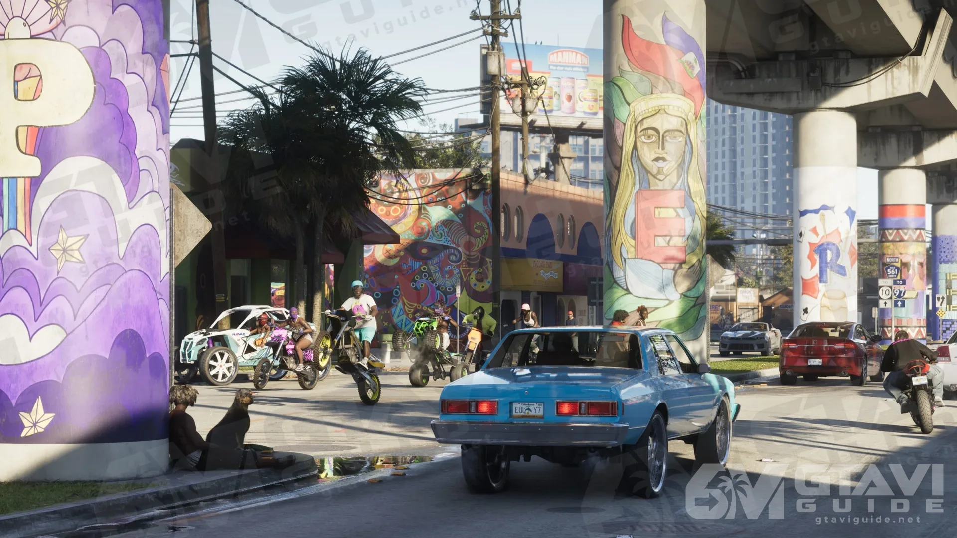 A blue classic car and stunt bikers under mural-covered overpass pillars in Vice City